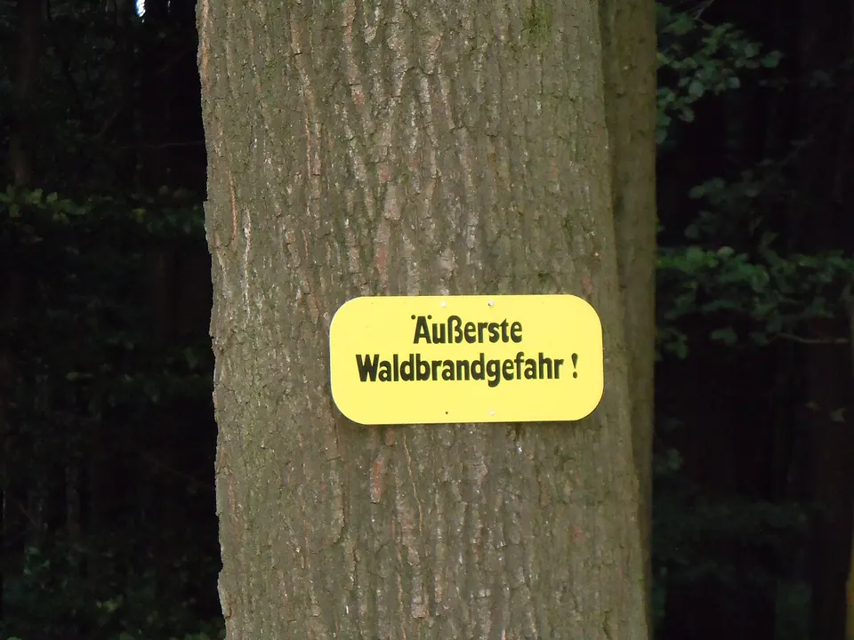Gelbes Schild »Äußerste Waldbrandgefahr!« an einem Baumstamm