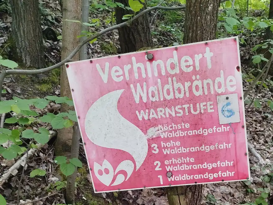 Rotes Warnschild »Verhindert Waldbrände« mit Warnstufen an einem Baum in Niesky